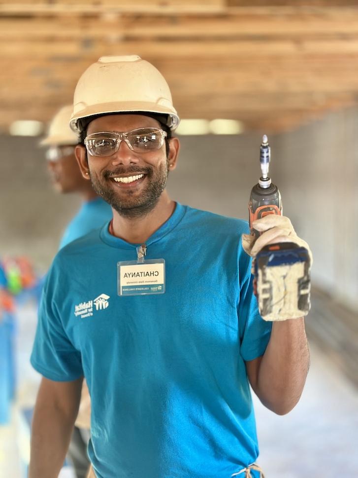 Student smiling and holding electric drill on construction site